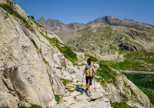 Guest hiking along rocky cliffside, river to her right.