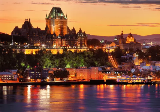Wide shot of the Fairmont Le Château during sunset, river in foreground.