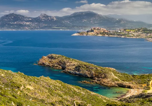 Wide shot of Italian lakeside, large peninsula, hills, coastal town in distance.