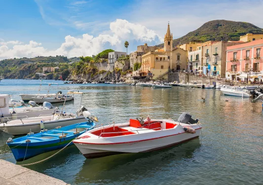 Point of view shot of pier, boats, ocean, hillside, seaside town.