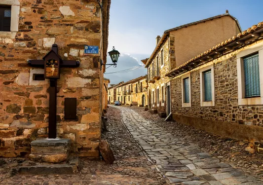 Alleyway shot of stone-built town, windows, doors dot the alley.