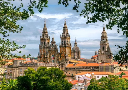 POV shot of Cathedral of Santiago de Compostela, taken from distant treeline.