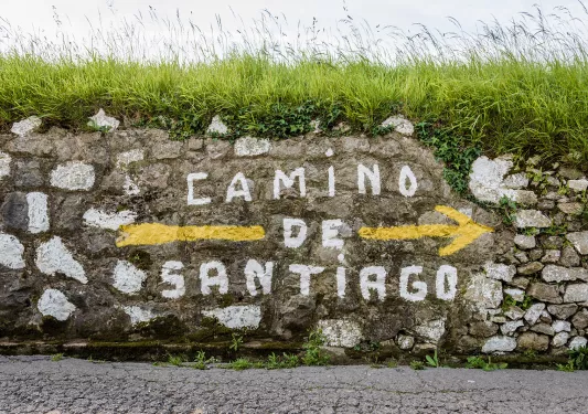Shot of stone wall with "Camino de Santiago" painted on it.