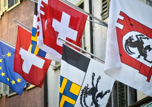 Swiss flags hanging on side of hotel. 