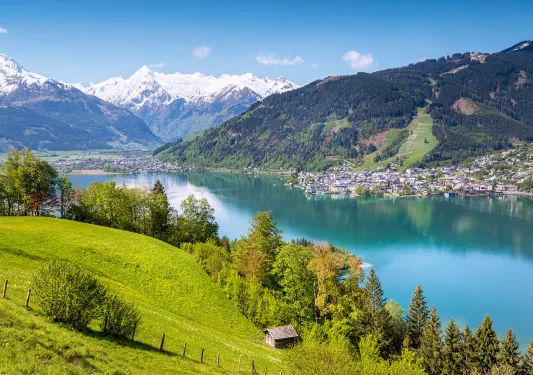 Wide shot of hilly vista, riverside town and mountains in distance. 
