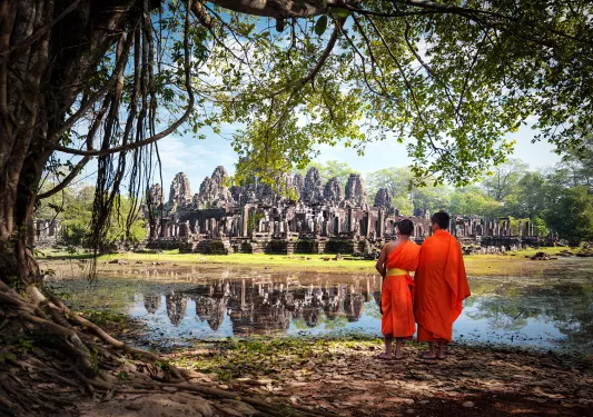 Two monks in traditional orange robes looking at Angkor Wat in Cambodia