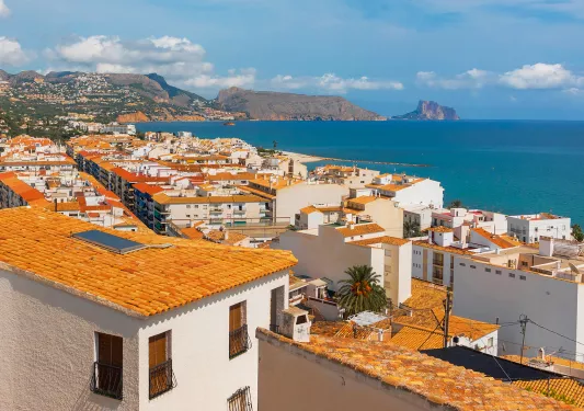 Shot of coastal town, white and tan houses, ocean.