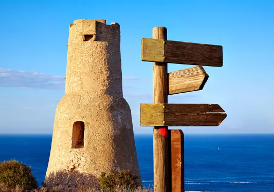 Shot of Torre del Gerro, wood sign, ocean behind.
