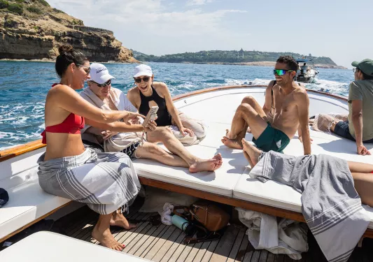 Six guests on boat, three looking at one of their phones.