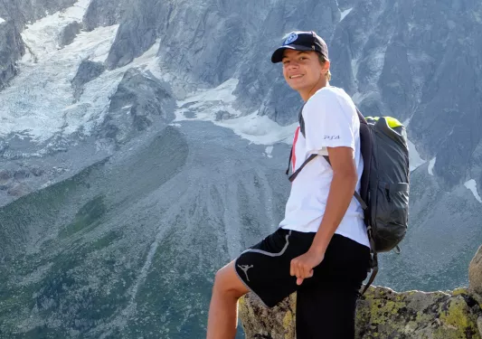 Young guest posing, mountain in the distance behind them.