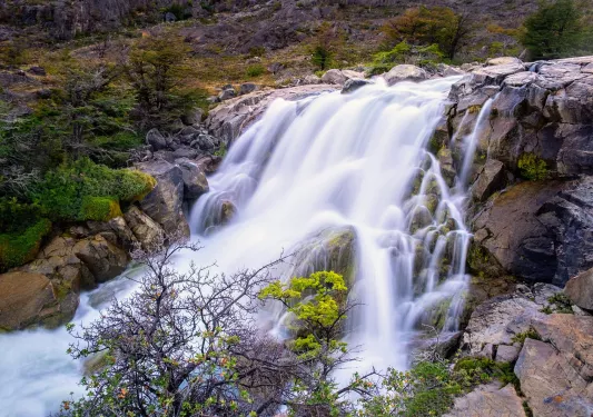 Shot of flowing waterfall, trees, river.