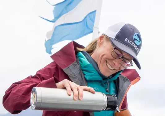 Leader pouring water into yerba mate infuser, Argentinian flag behind them.