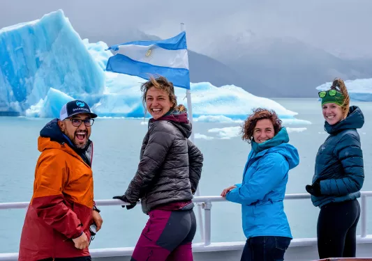 Four guests looking towards camera, blue glaciers behind them.