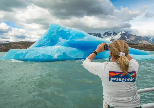 Woman on boat taking picture of a glacier in Patagonia.