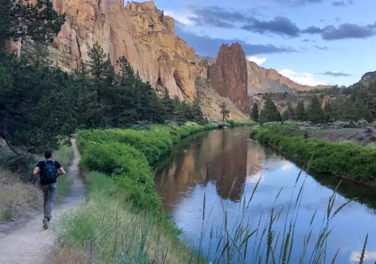 Guest running by small river in Smith Rock Park.
