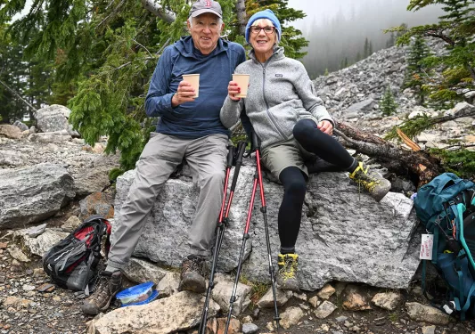 Two guests relaxing on rock, beverages in hand.