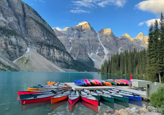 Canoe dock on lakeshore, mountain range in distance.