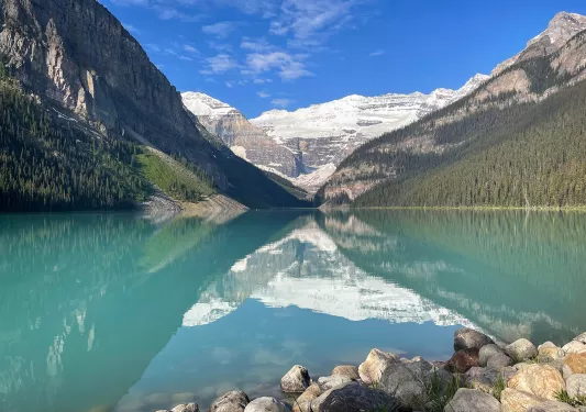 Wide shot of blue lake, mountains, clouds, sky.