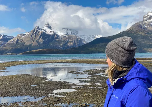 Guest looking out towards lake, mountains, clouds.