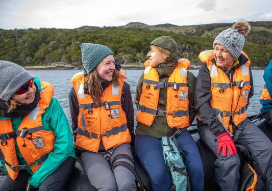 Four guests on raft in life-vests, all smiling.