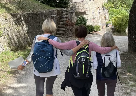 Three guests walking down Italian road, small stone shack in distance.