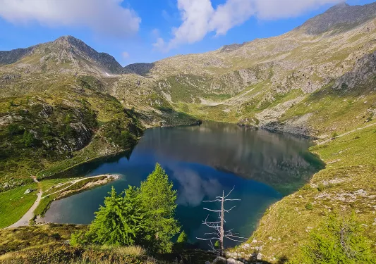 Wide shot of blue lake, ring of mountains all around.