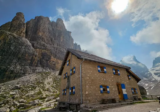 Ground shot of mountain chateau, craggy cliffs, sun.