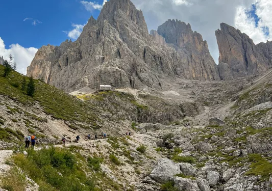 Guests walking up trail, large mountain looming in distance.