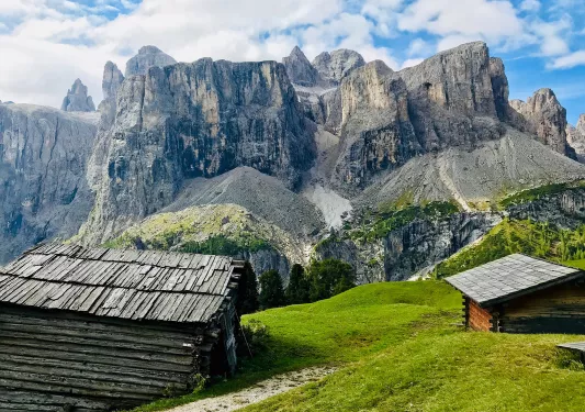 Shot of two old, wooden houses, angular cliffs in distance.