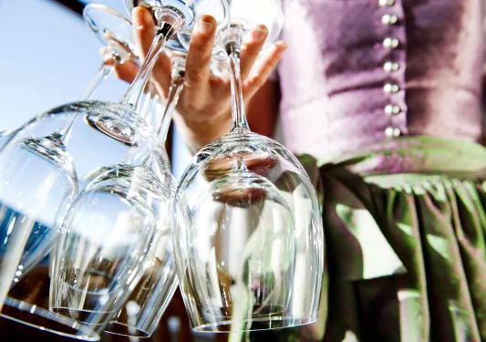 Shot of server carrying numerous wine glasses in one hand.
