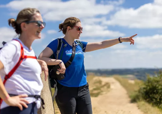 Two hikers on trail, pointing at view in the distance.
