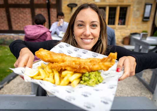 Backroads guest posing with fish and chips plate in England.