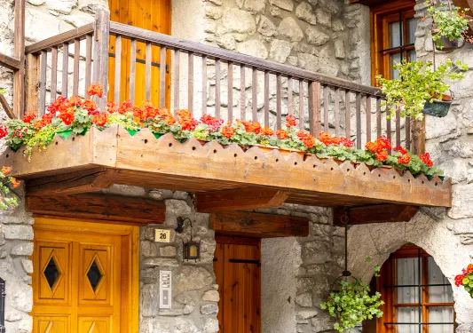 Housefront shot of stone building, wooden doors, balcony.