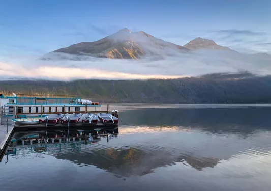 Fog wrapped around mountain in the background of reflective lake