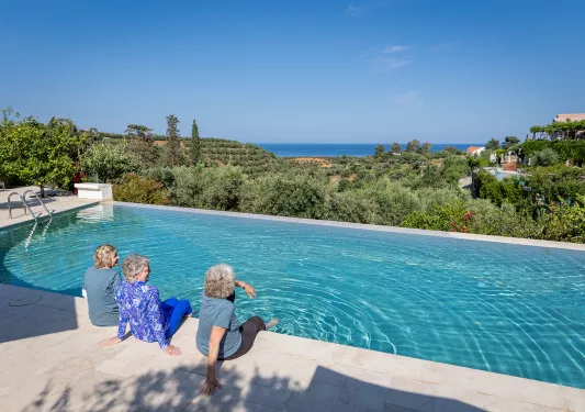 Three women resting by a hotel pool in Greece.