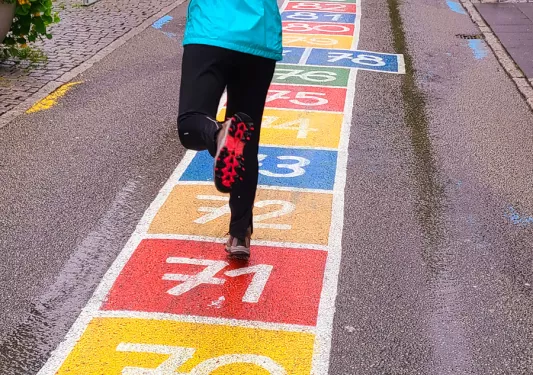 Backroads guest playing hopscotch on chalk drawn sidewalk.