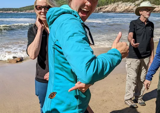 Guest/leader smiling at camera, butterfly on their back.