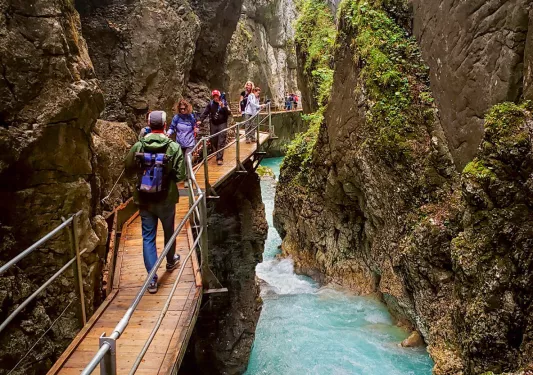 Hikers on bridge over waterfall in Bavaria.