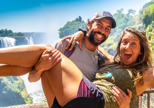 A man holding a woman in his arms, both laughing