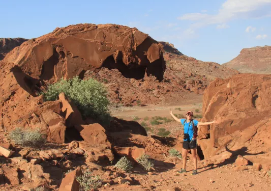 A woman standing among boulders with arms outstretched