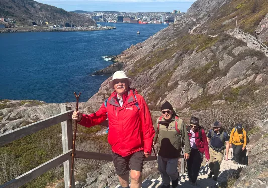 Guests hiking up hillside stairs, ocean in background.