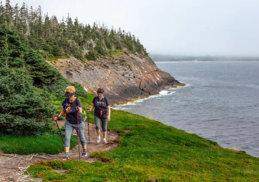 Two guests walking alongside coastal cliff.