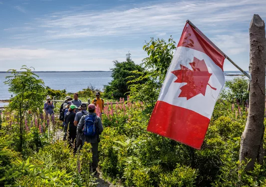Guests in coastal garden, Canadian flag in foreground.