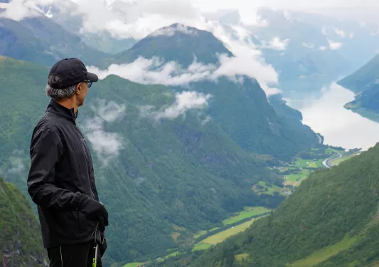 Solo hiker looking out over a lush green valley in Norway