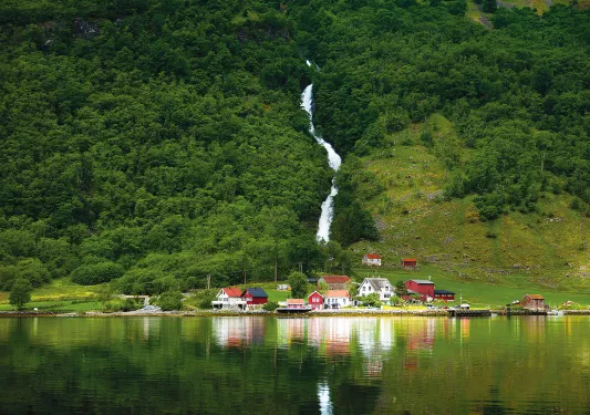 Waterfall cascading down a green grassy hill in Norway