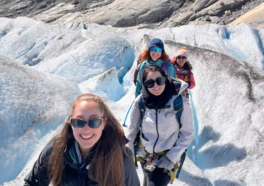Four women hiking up a snow packed mountain trail.