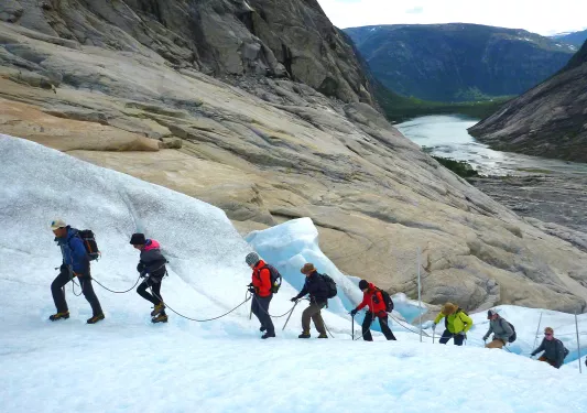 Hikers climbing an icy glacier in a single file line