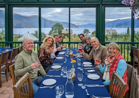 Group of hikers enjoying a meal together while overlooking a fjord and mountains