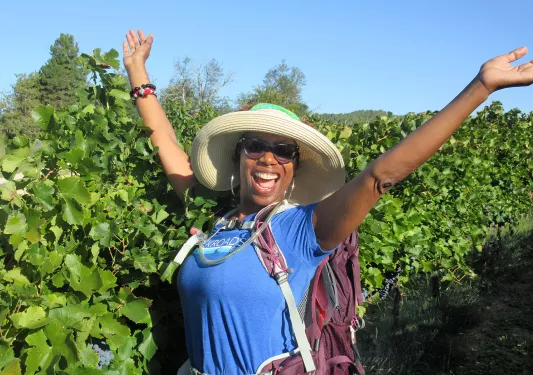 Backroads Guest in Front of Grape Vines with Hands in the Air 