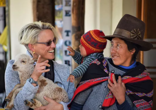 Guest holding baby sheep, with two locals.